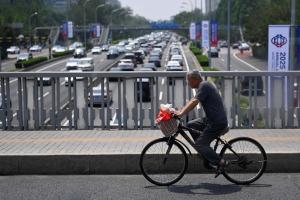 中国强制社保未解决养老保险体系存在的问题。一名老年人在北京一座立交桥上骑着脚踏车，摄于6月18日。（法新社）